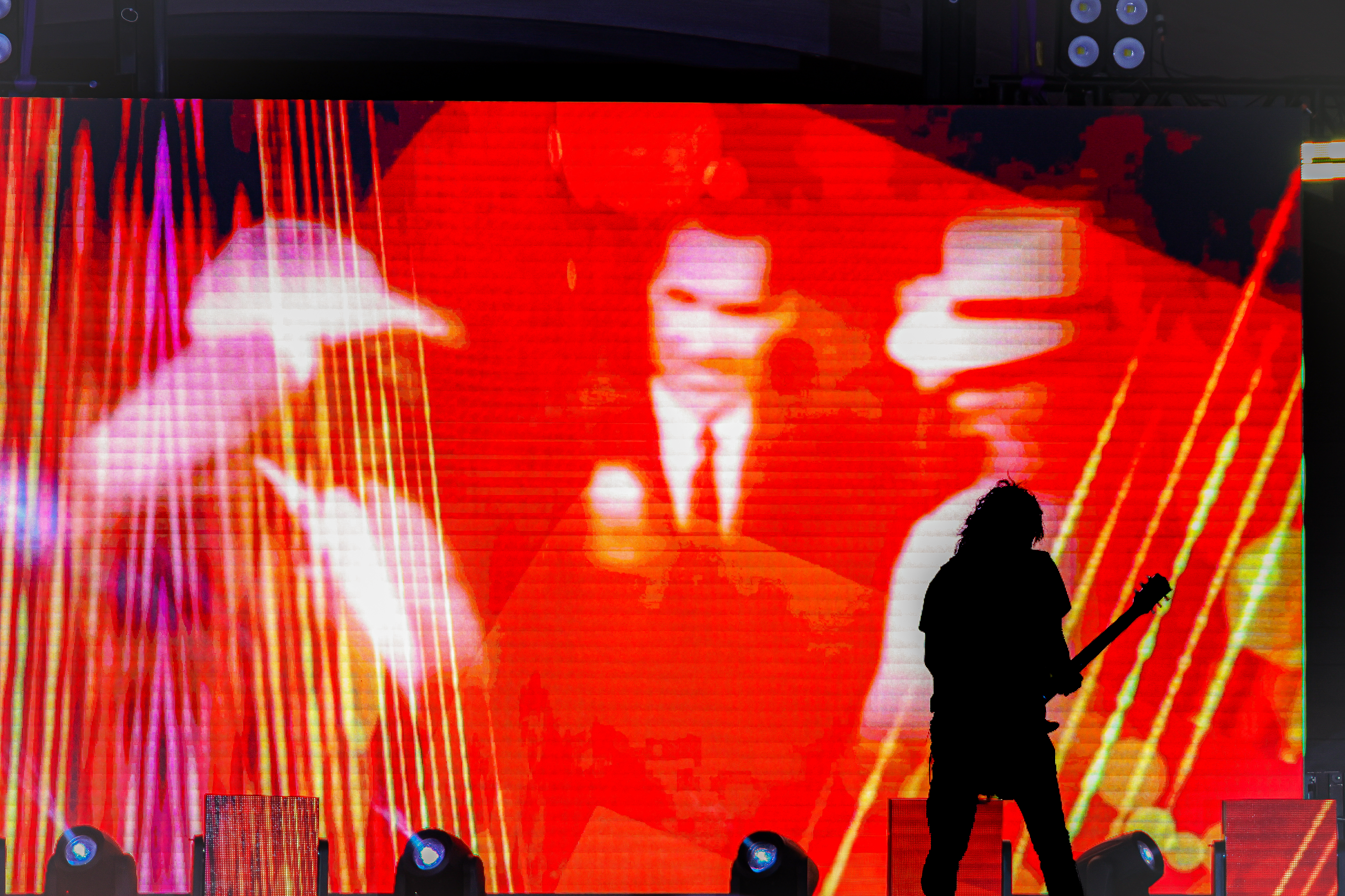 Guitarist silhouette against LED stage visuals.